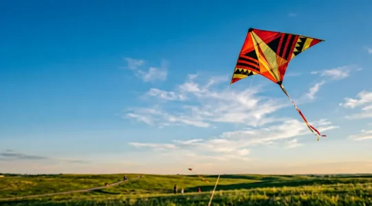 Cerf-volant artisanal aux couleurs vives flottant dans le ciel bleu, fabriqué avec des matériaux créatifs