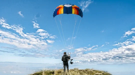 Cerf-volant de photographie aérienne en vol avec nacelle suspendue portant une caméra dans un ciel dégagé