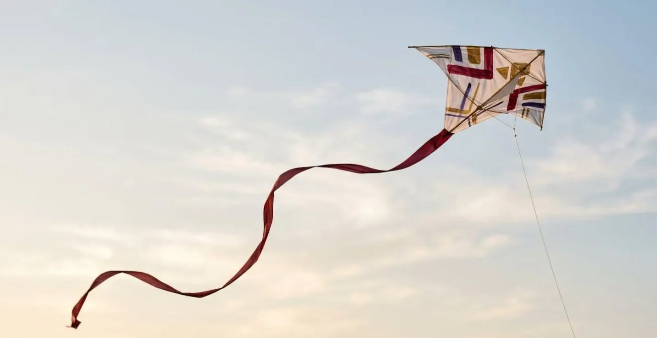 Cerf-volant traditionnel asiatique avec motifs calligraphiques en vol, créant des lignes fluides dans le ciel