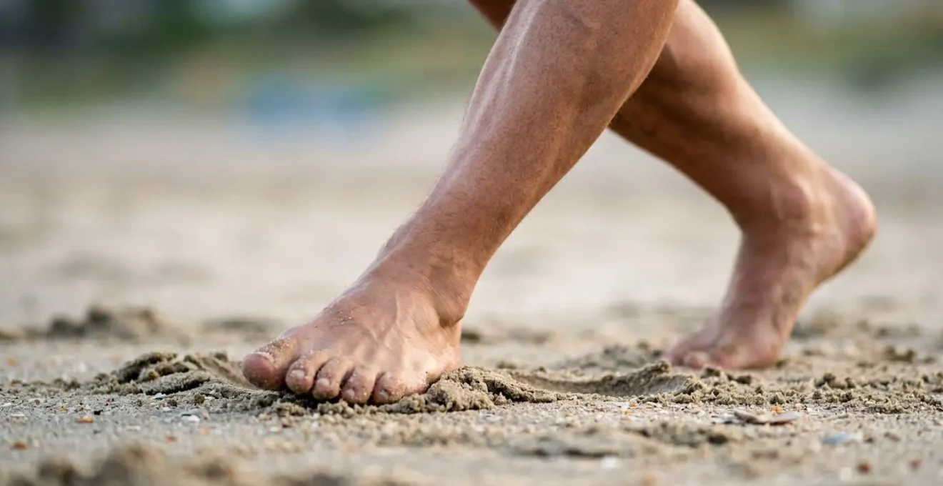 Vue rapprochée des jambes et du bas du corps d'un pilote de cerf-volant en position de fente sur le sable