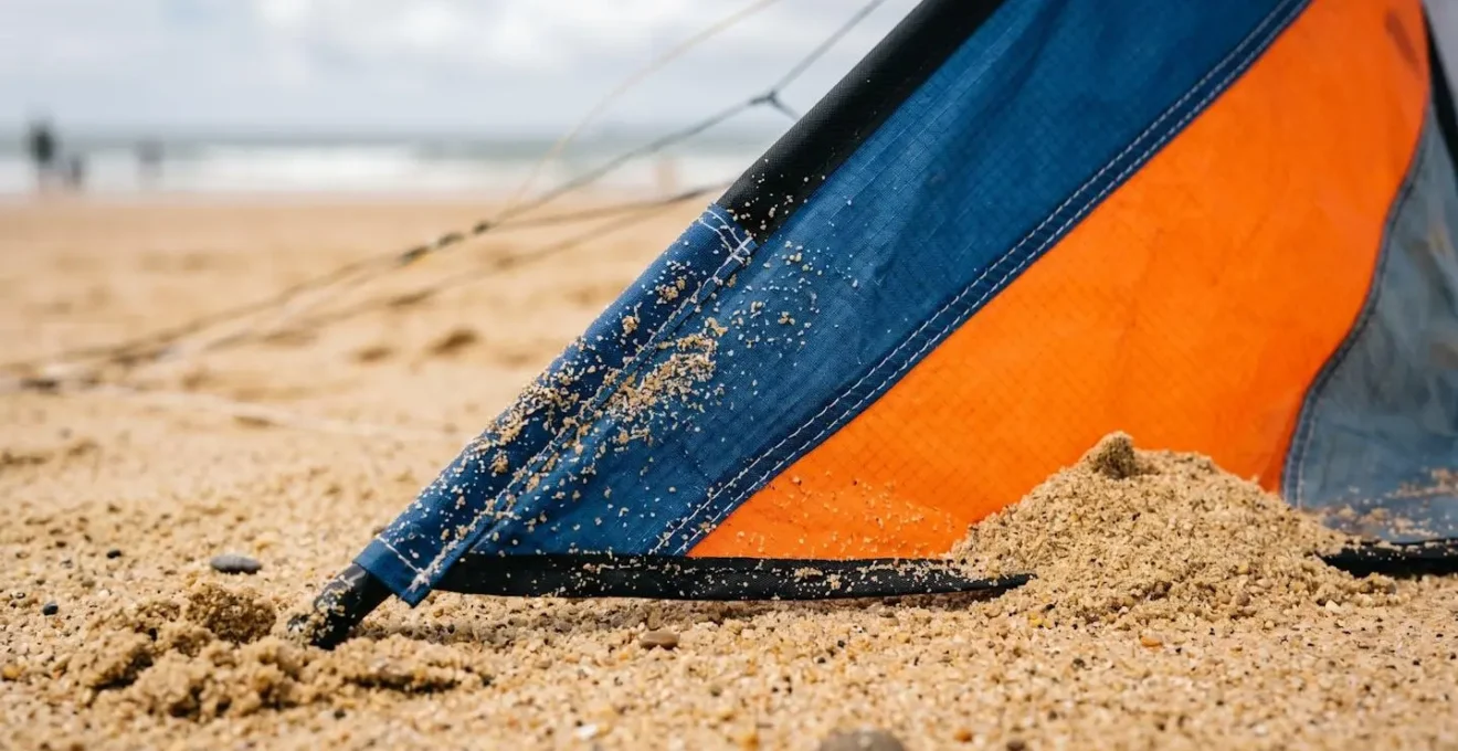 Gros plan sur un cerf-volant acrobatique positionné au sol maintenu par du sable avant le décollage