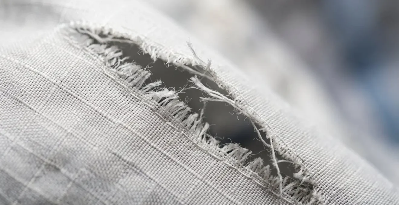 Gros plan sur une déchirure de tissu technique montrant la texture et la structure du matériau endommagé